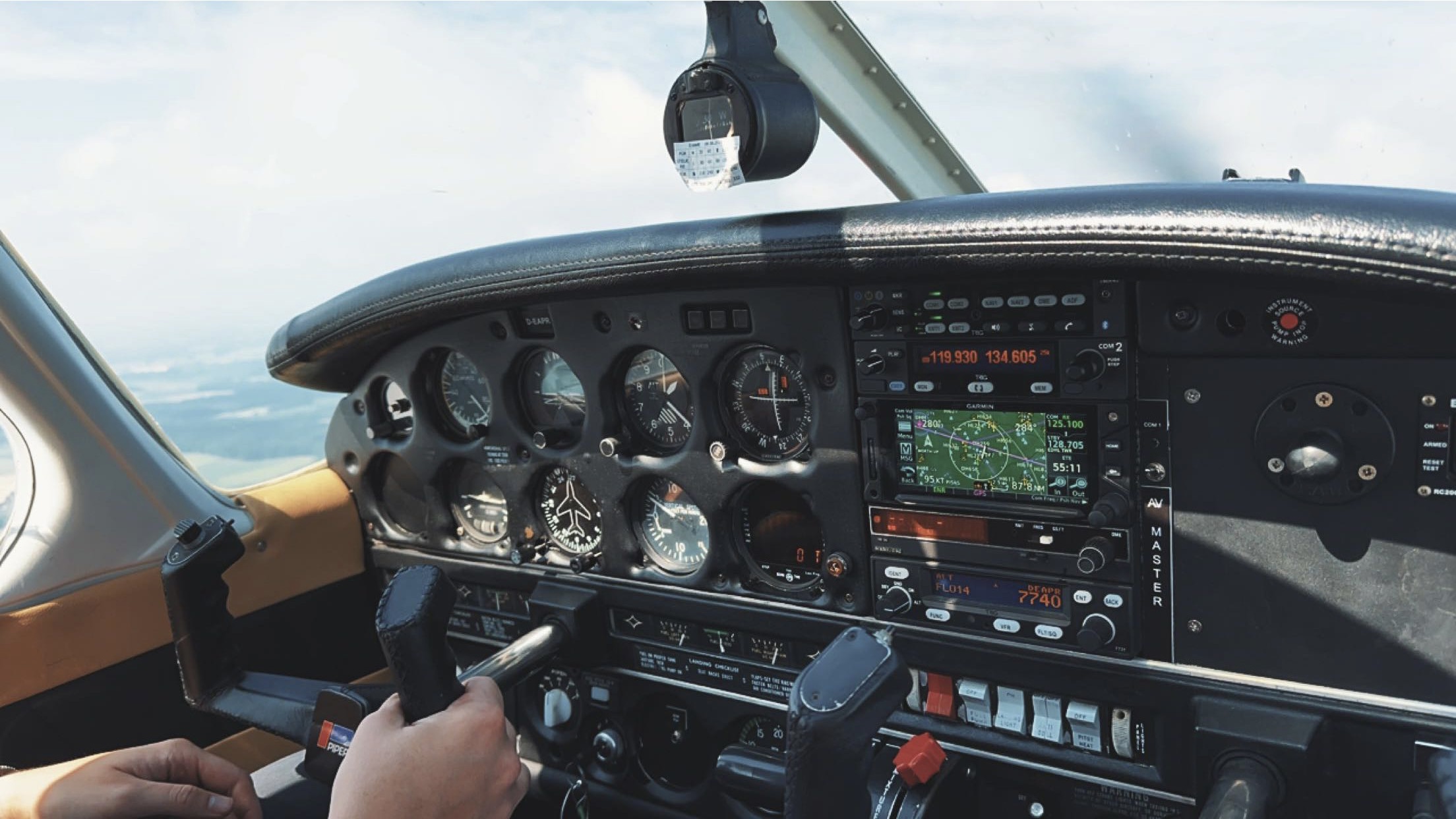 Das Cockpit einer Piper PA-28 während des Fluges. Eine Detailaufnahme mit Blick auf die Instrumente und das Steuerhorn.