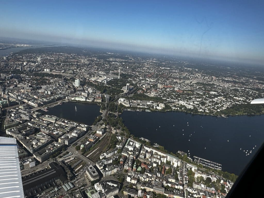 Panorama Hamburg Innenstadt mit Alster und Fernsehturm während eines Rundfluges über Hamburg. Der Himmel ist Blau ohne Wolken.